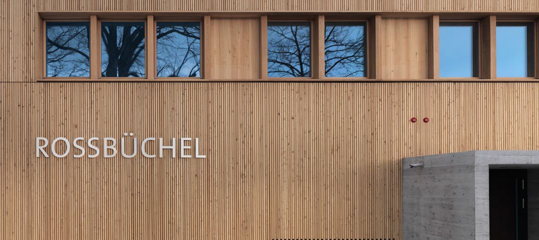 Holzfassade aus feinen senkrechten Latten mit dem Schriftzug Rossbüchel